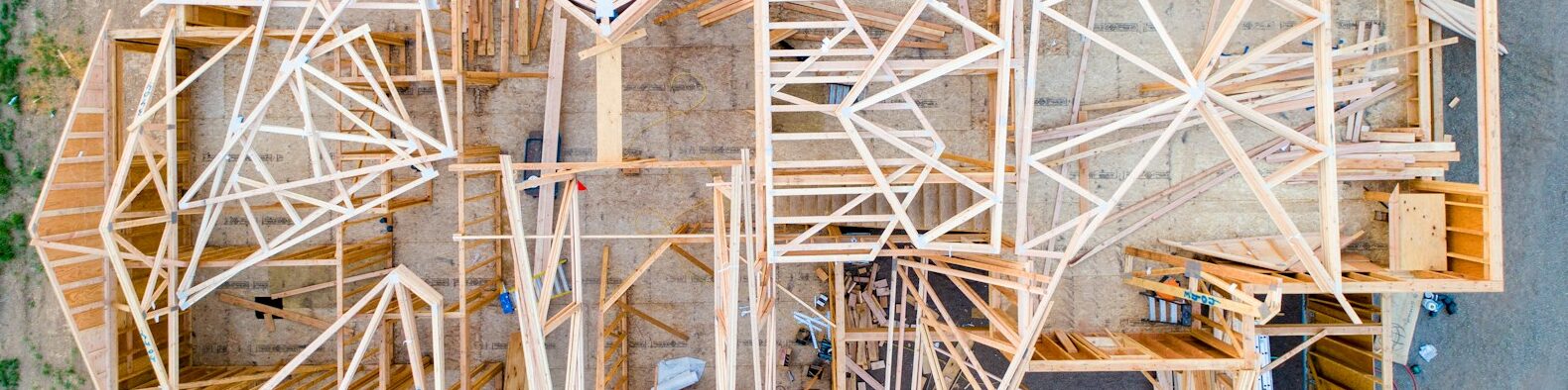 Le chantier d'une maison, vu du dessus. La structure en bois est visible et elle n'est pas terminée.